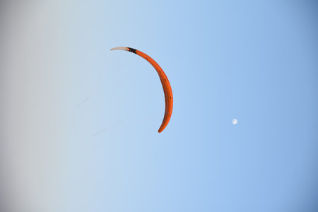 Paraglider flying in the blue sky. Extreme sport. the moon in the background