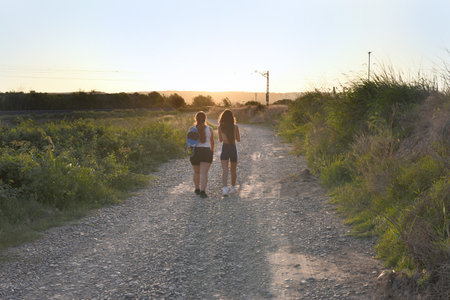 Young couple walking on a country road in the countryside at sunset.の写真素材