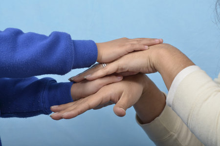 Mother and son holding hands, close-up, on blue background