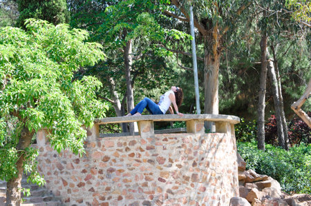 Woman sitting on a stone bench looking at the skyの写真素材