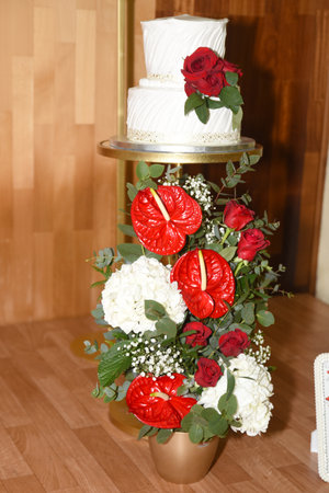Wedding cake decorated with white and red flowers and red roses on a golden standの写真素材