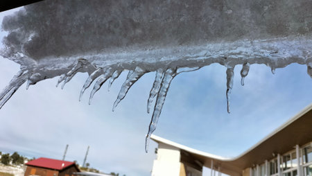 Icicles hanging from the roof of a house in winter.の写真素材