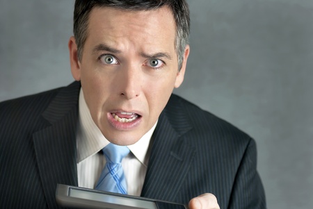 A close-up shot of a businessman looking to camera confused by his tablet computer.の写真素材