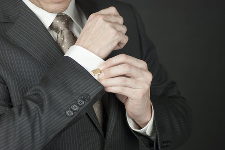 Close-up of a businesman adjusting his cufflink.