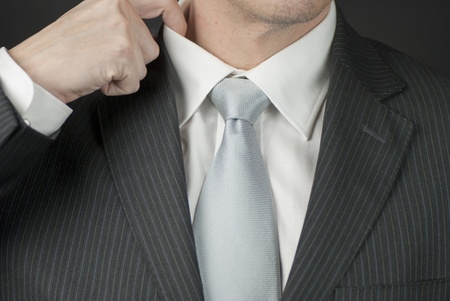 A close-up of a businessman adjusting his collar.の写真素材