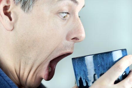 Close-up of a man looking in his mug in amazement.の写真素材
