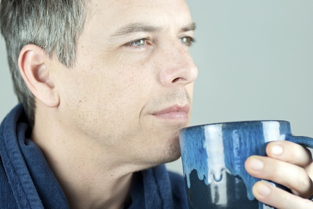 Close-up of a serene man holding his mug and looking off camera..の写真素材