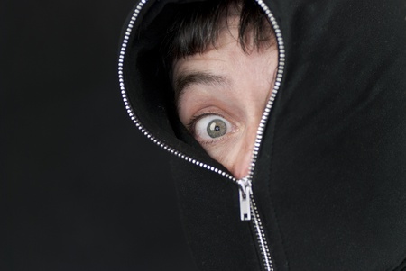 Close-up of a shocked man with the hood of his sweatshirt zipped up to his eye.の写真素材