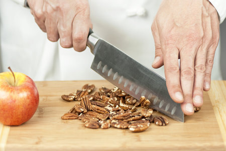 Close-up of a chef chopping pecans.