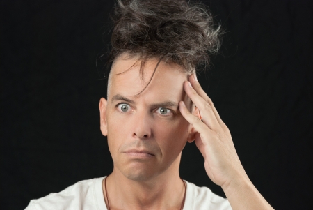 Close-up of a man thinking, hand to head, looking off camera, hair piled on his head の写真素材