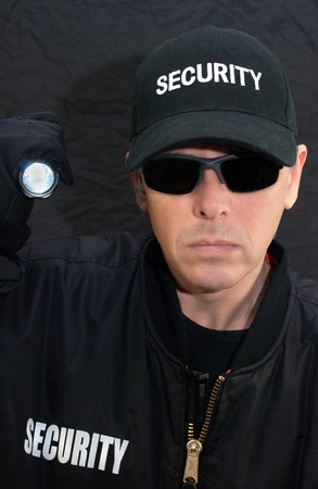 Close-up of a security guard shining a flashlight at the camera.の写真素材
