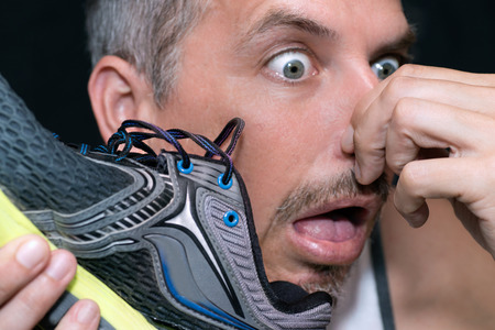 Close-up of a man gagging after smelling his running shoe.の写真素材