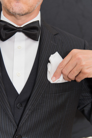 Close-up of a gentleman wearing Black Tie fixes his pocket square, vertical.の写真素材