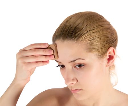 young woman putting make up on her face. Isolatedの写真素材
