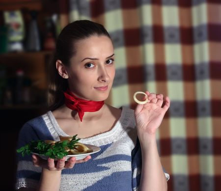 Young woman eating fried calamar in kitchenの写真素材