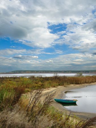 Landscape with wooden boat on autumn lakeの写真素材