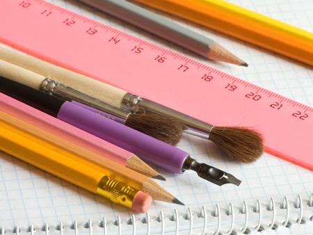pencils and brushes on squared sheet of a copybookの写真素材