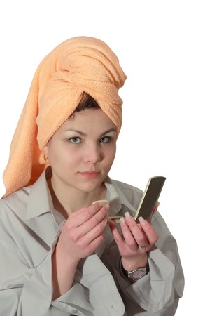 young woman putting make up on her face. Isolatedの写真素材