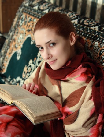 young woman reading book on sofa at homeの写真素材