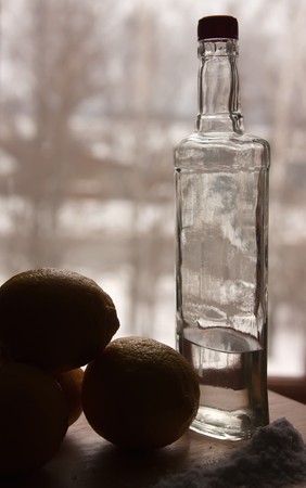  Bottle of tequila and salt against wintry windowの写真素材