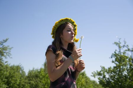 Young girl blowing seeds of a dandelion flowerの写真素材