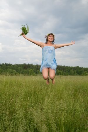 Jumping sexy girl in flower chaplet against cloudsの写真素材