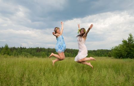 Jumping girls in flowers wreath  against cloudsの写真素材