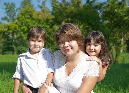 Happy mother with her children sit in grassの写真素材