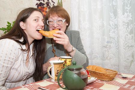 Two smiling womans have tea with tasty cookies in the kitchenの写真素材
