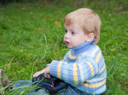 Little boy sitting on grass in park の写真素材