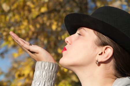 Air-kissing girl in felt hat  at autumn parkの写真素材
