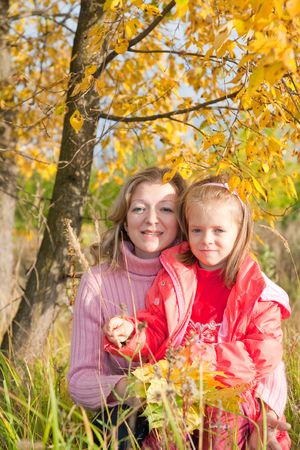 mother with little girl against autumn park の写真素材