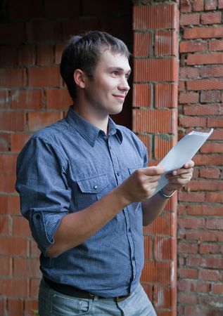 Happy businessman with documents against  the brick wallの写真素材