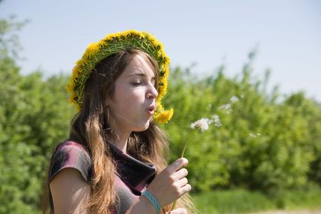 Young girl blowing seeds of a dandelion flowerの写真素材