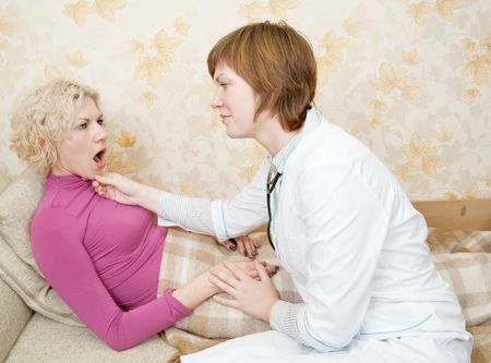 Female doctor loking to suffering girl on bedの写真素材
