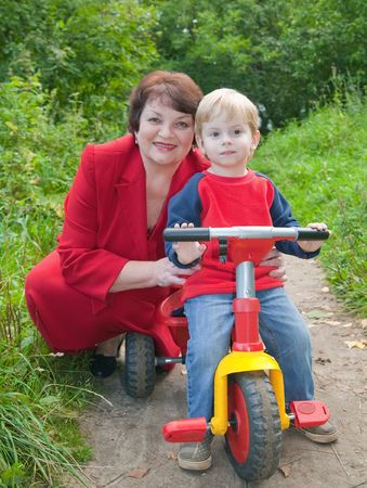 grandmother with boy on tricycle at natureの写真素材