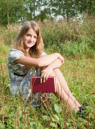 Girl with book at green grass from meadowの写真素材