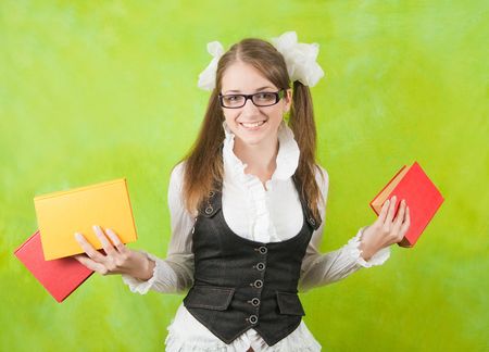 schoolgirl in glasses with books over green backgroundの写真素材