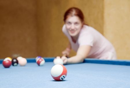 young woman playing billiards looking at camera. Focus on ballの写真素材