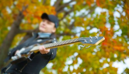 Teenage girl with electric bass guitar against autumn nature, Focus on guitar onlyの写真素材