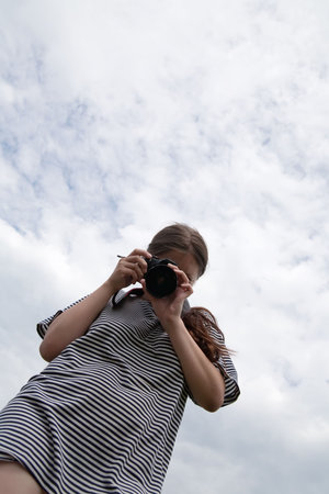Young female photographer  against cloudy sky