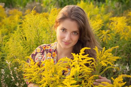 long-haired teen girl in grass during sunsetの写真素材
