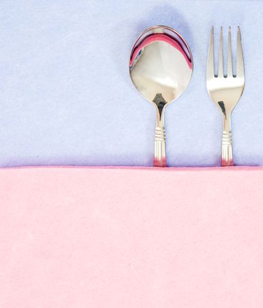 silvery spoon and fork, covered by a nice pink napkin の写真素材