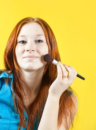 Girl putting facial powder on her face with a brushの写真素材