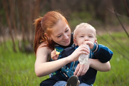 mother with son drinking water on meadowの写真素材