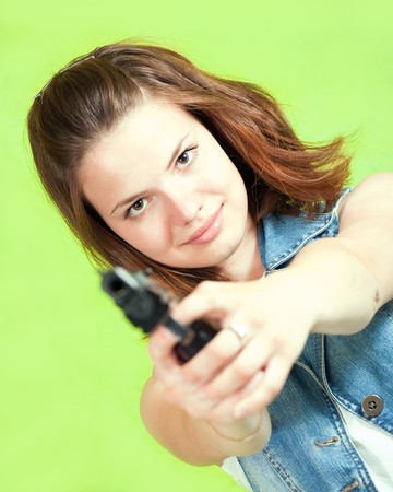 Pretty girl  aiming a black gun over greenの写真素材
