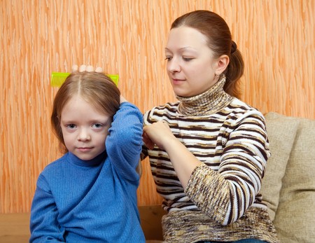 mother combs the hairs of daughter at homeの写真素材