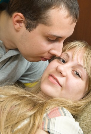 Young couple in love  on the couch kissingの写真素材