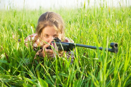 young girl aiming pneumatic air rifle outdoorの写真素材