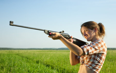 girl  aiming a pneumatic air against summer field